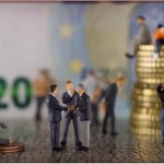 Giocatori di Affari Tuoi sorridono durante una puntata, con buste e premi in evidenza.